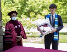 Portrait of President Valerie Smith in regalia with graduation gift for student