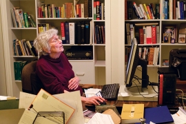 An older woman sits in an office with books. Christine Parker Ammer ’52 has turned her fascination with words into a career as a  lexicographer.