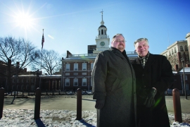 two men stand in Philadelphia in winter coats