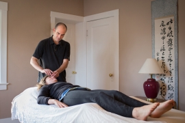 male practitioner performs acupuncture on female patient