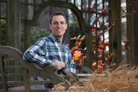 Josh Coceano sitting in a beautiful nature setting with autumn leaves