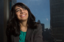 Urooj Khan ’10 in a suit, looking up as the sun shines behind her.