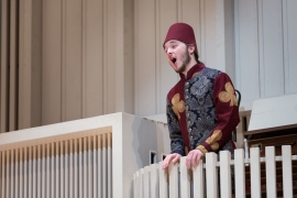 costumed male student orates while standing on a balcony