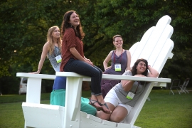 alumni sit on a big adirondack chair smiling