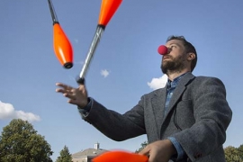 John Rieffel juggling in a suit and clown nose