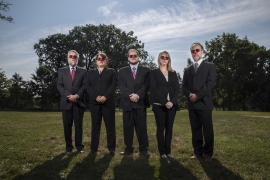 Bulletin staffers standing on Parrish Beach wearing dark suits, sunglasses, and clown noses