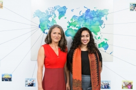 Morgan Simon ’04 and Jasmine Rashid ’18 standing in front of a world map