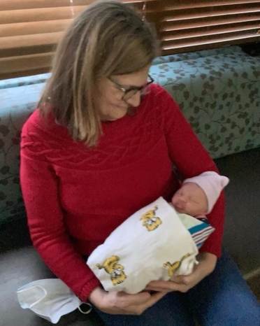 Woman in a red shirt cradling a new born baby