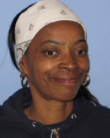 Photo of a woman smiling wearing a white bandana.