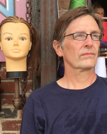 Man with glasses poses next to a mannequin head