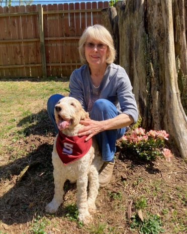 Woman poses with her dog who wears a garnet Swarthmore bandana.