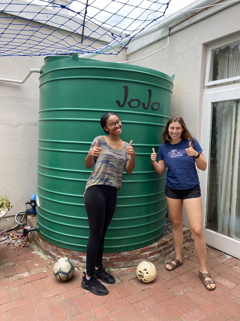 2 students standing in front of a rainwater catchment system