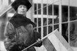 Black and white image of a woman holding a flag as she campaigns for women's suffrage