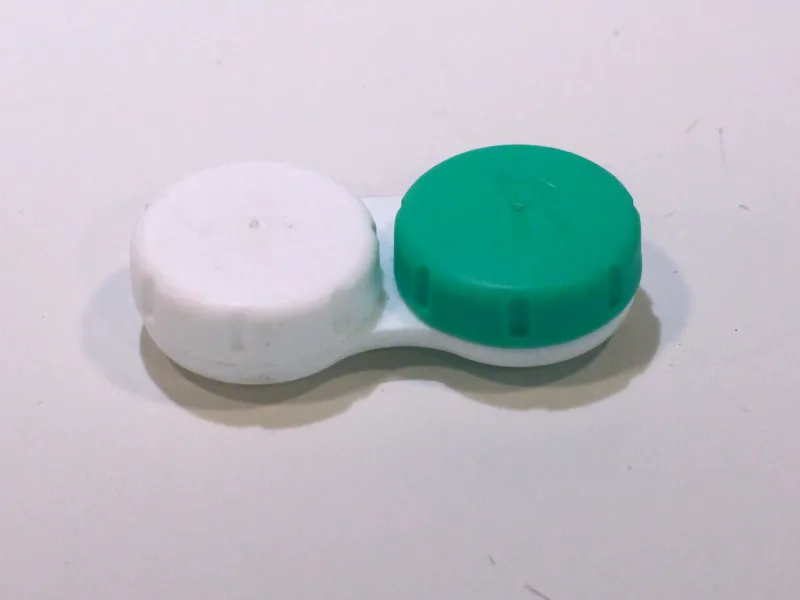 A standard plastic contact case with one white lid and one green