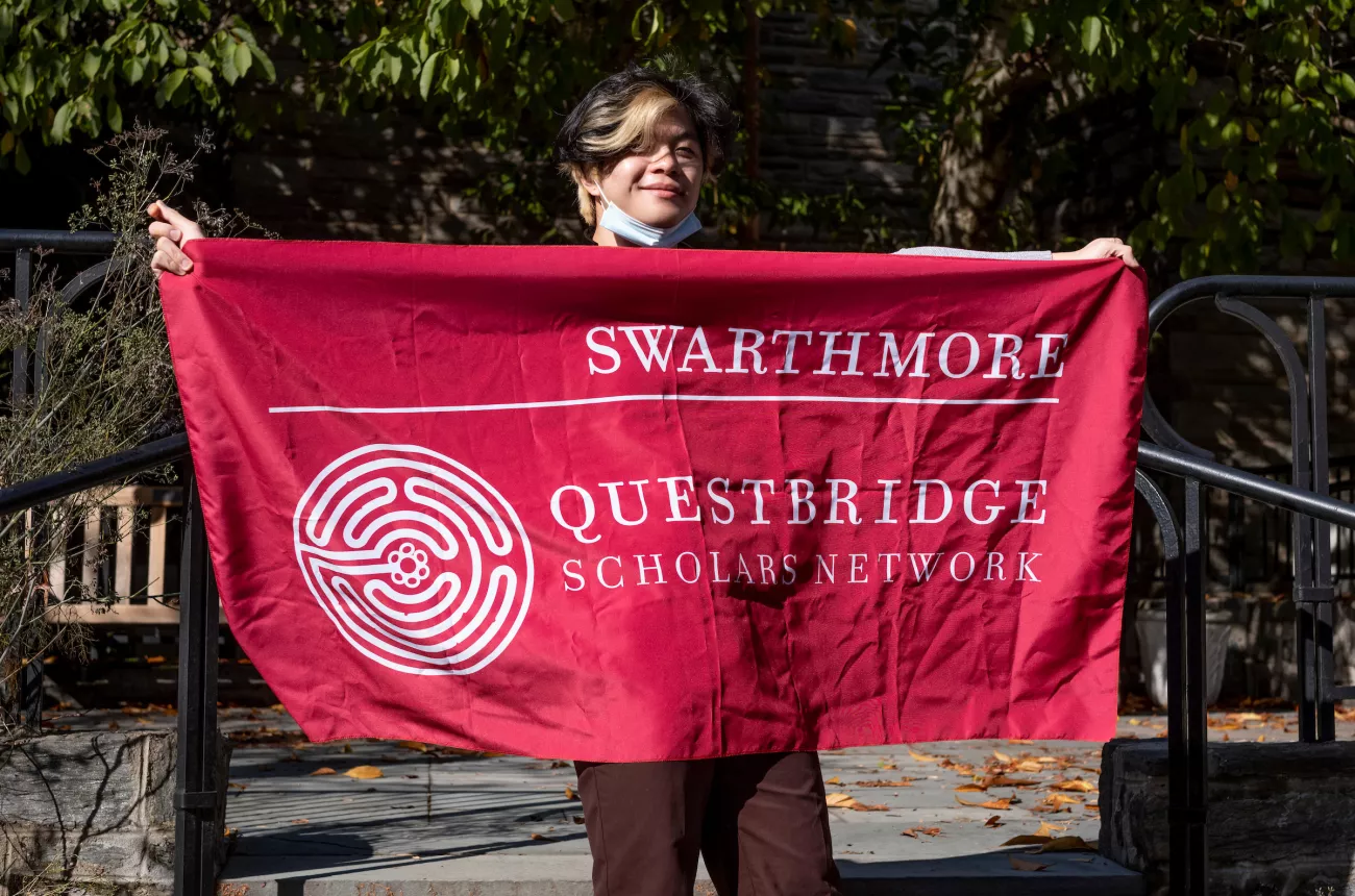 Student holding a flag that says "Swarthmore QuestBridge Scholars Network"