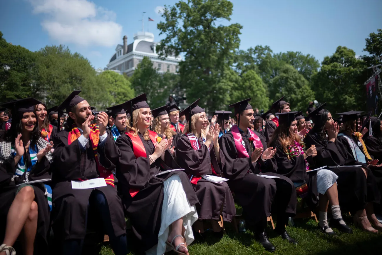 Students in regalia applauding at graduation
