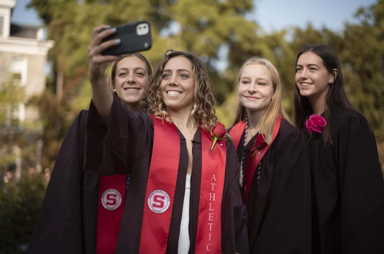 Four students smiling and taking a selfie on commencement day