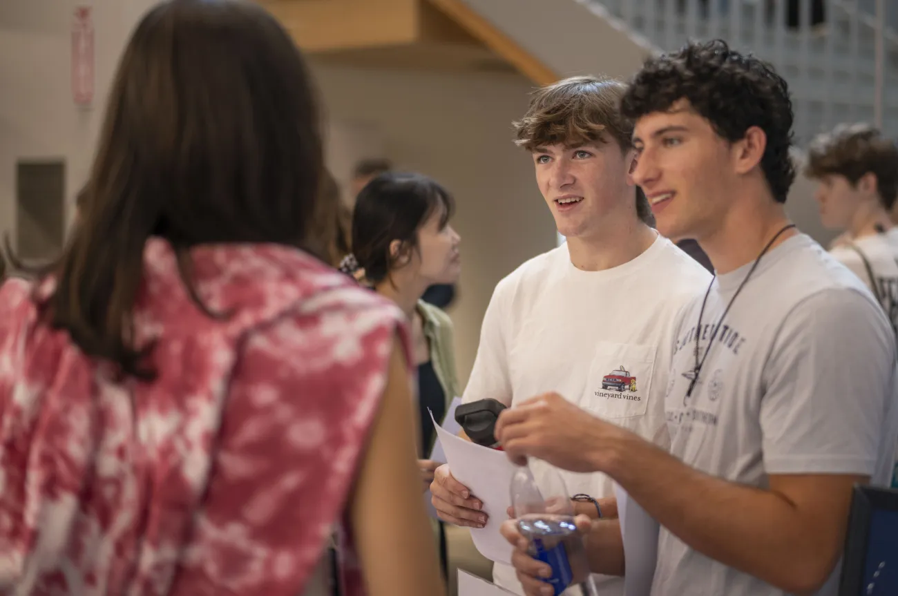 Two students smiling and talking to an advisor