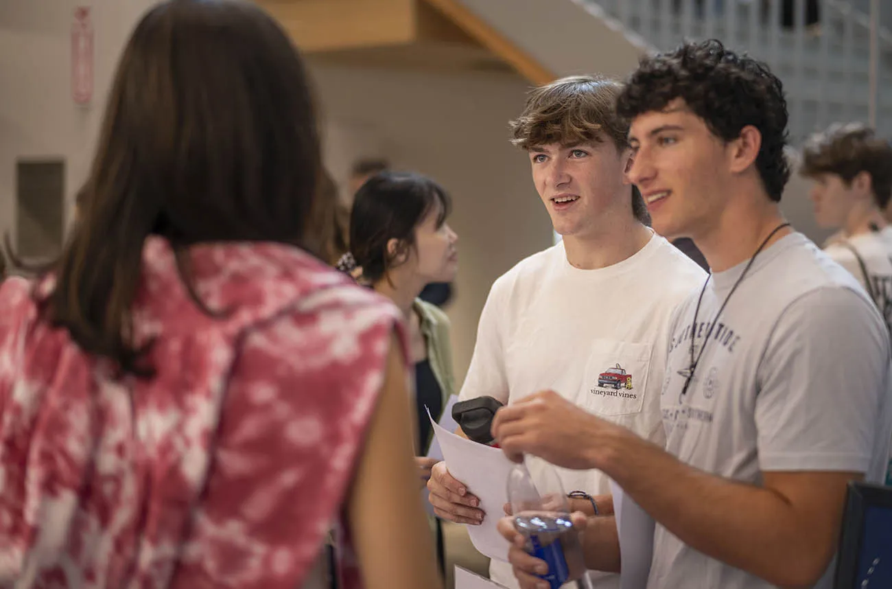 Two students smiling and talking to an advisor