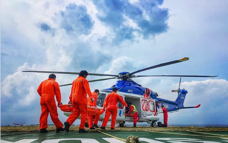 Crew from International SOS in orange jumpsuits alongside a medical helicopter