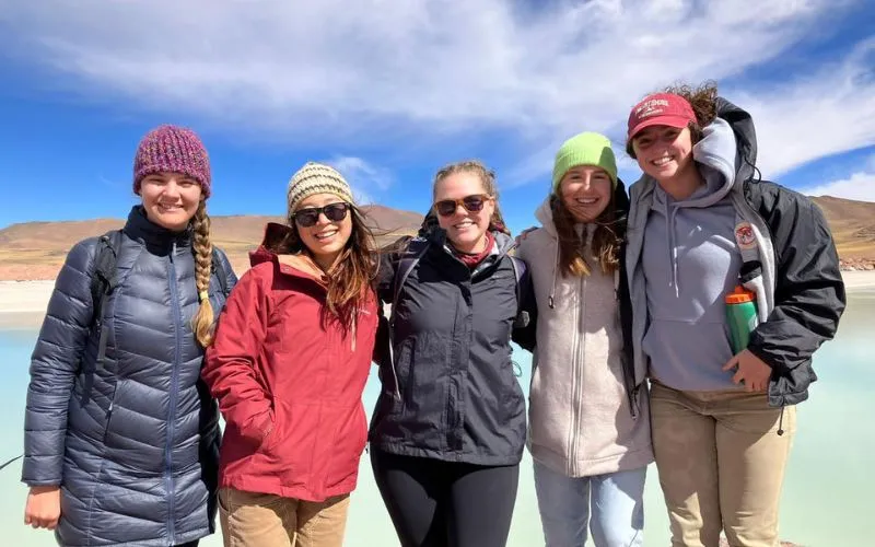 First female students stand shoulder to shoulder in front of hot springs in Chile
