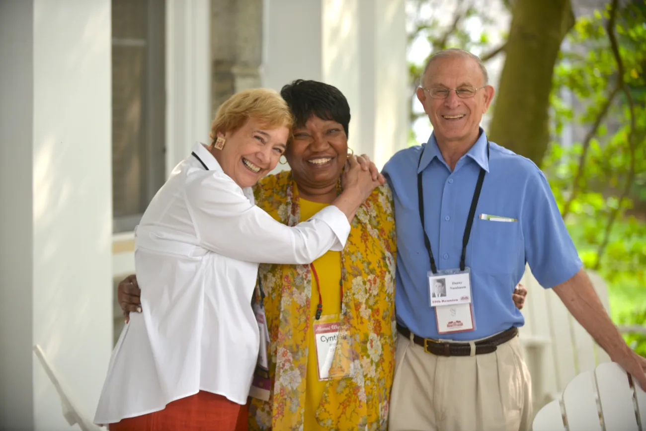 3 Alumni embracing and celebrating during an event