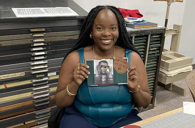 Student Kayla Walker holding a zine she made in a workshop