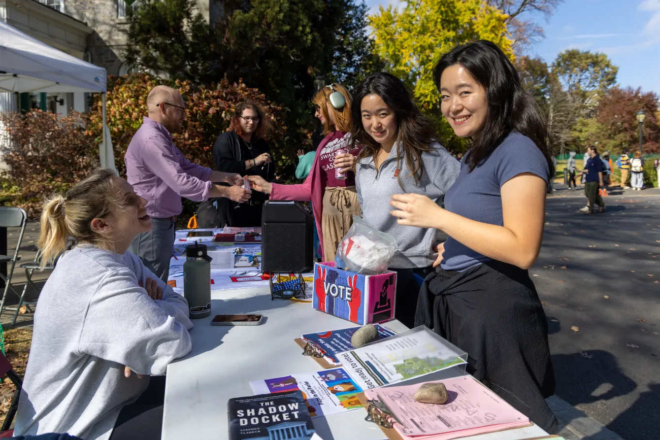 Staff helping students with voter information at an outside table