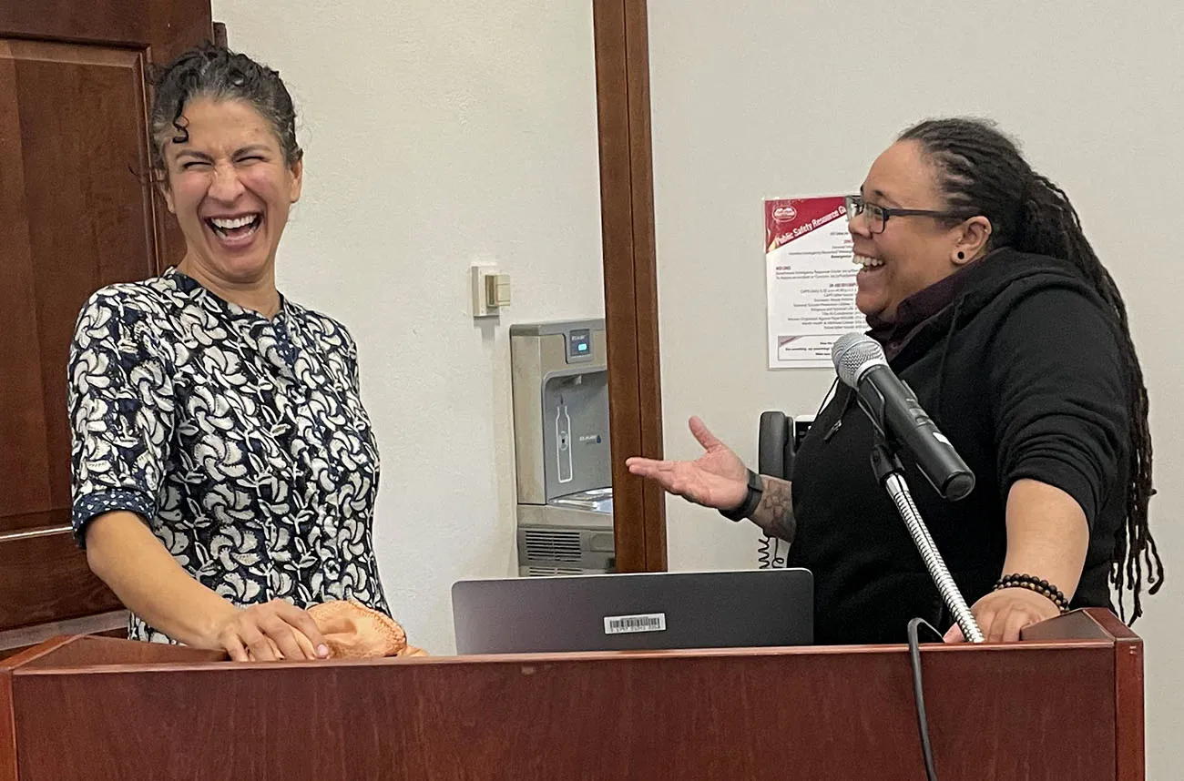 two staff members laughing at a podium