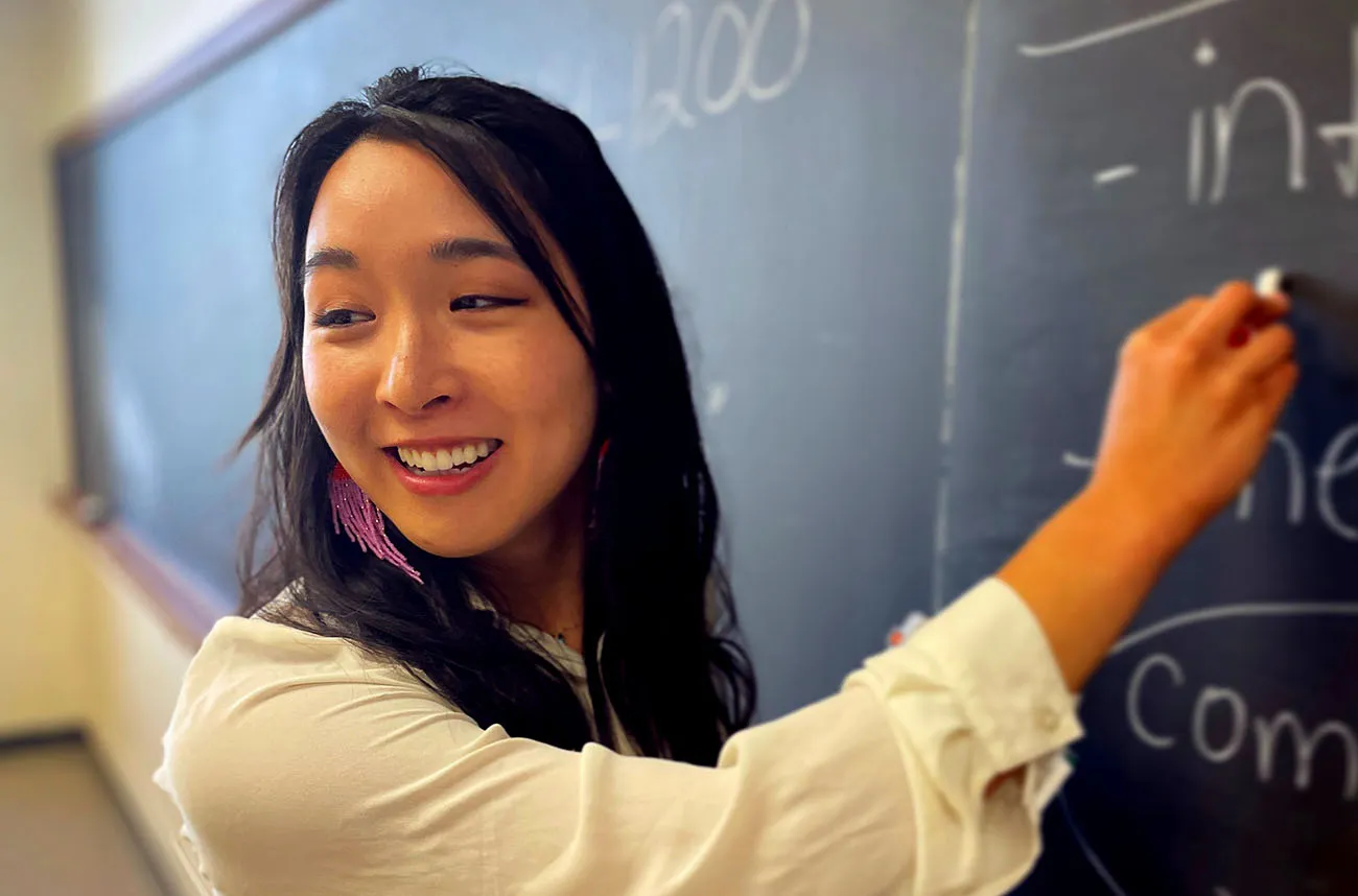 staff member smiling at blackboard