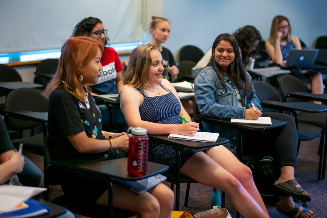 Three students in class, engaged in the lecture.
