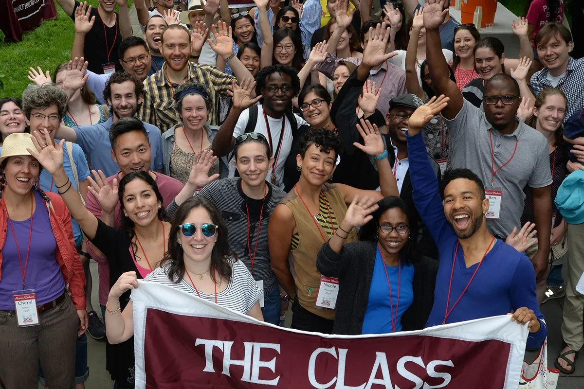 Alumni wave at camera during Parade of Classes
