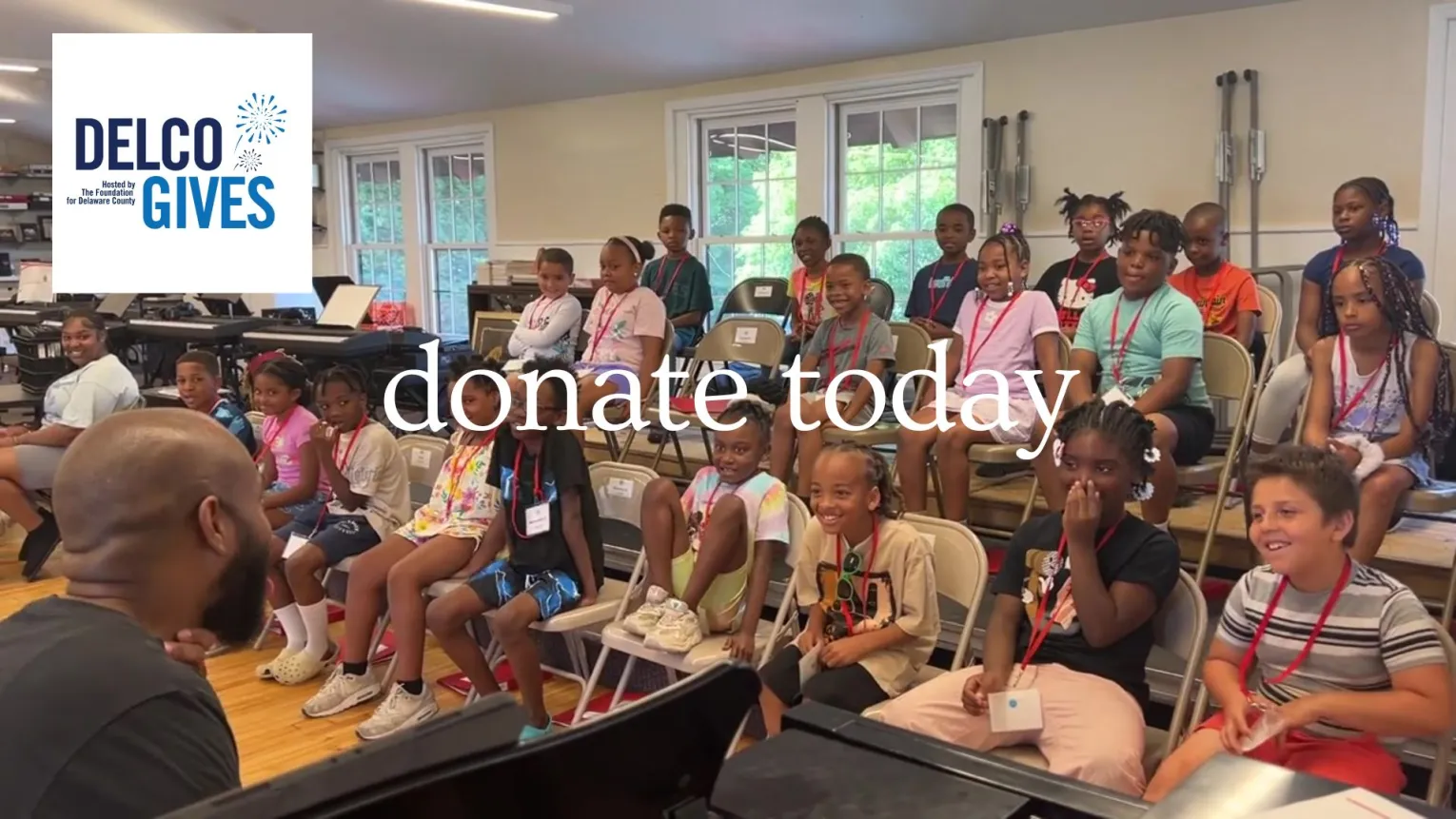 children in a choir sitting in front of the teacher