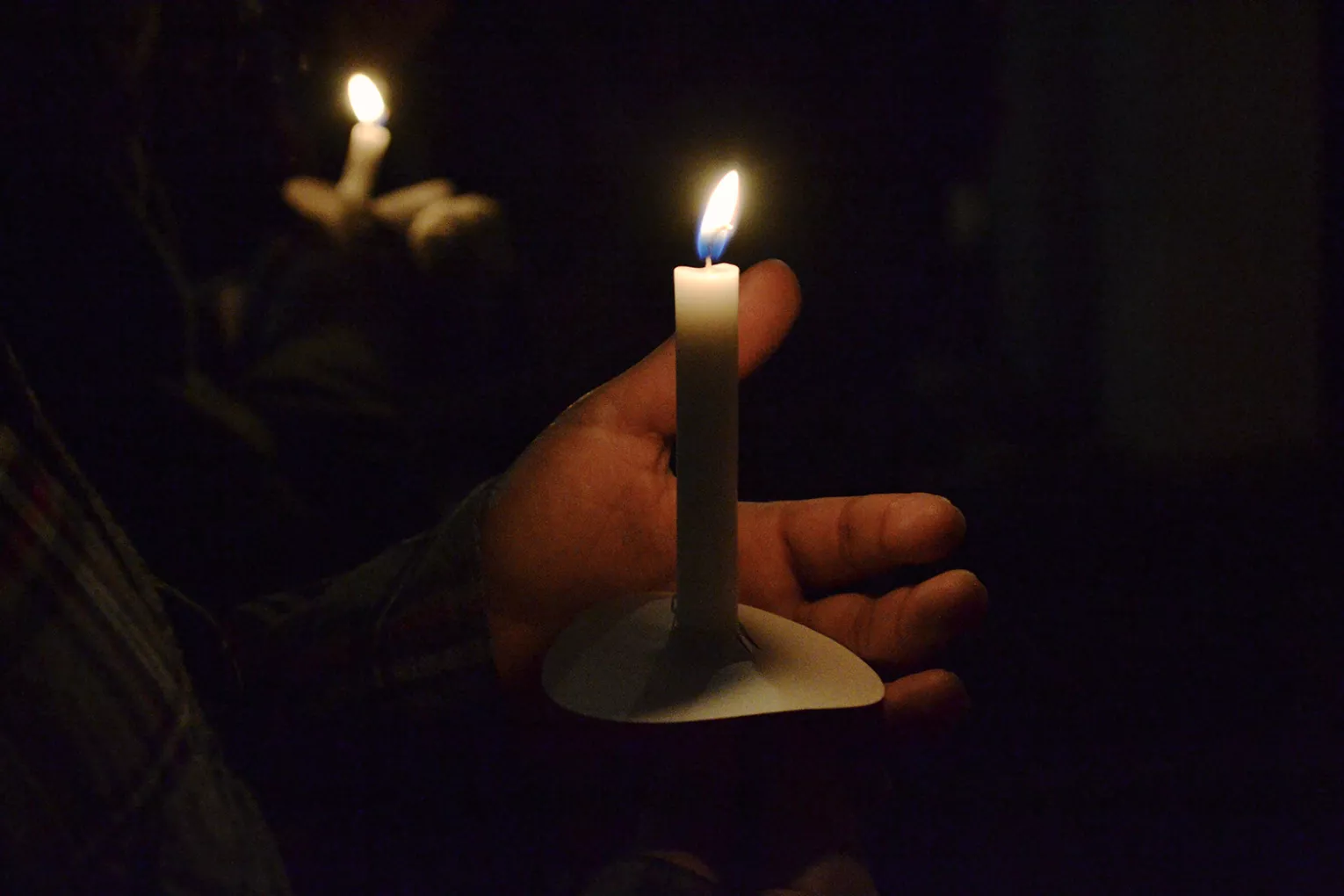 Student holds candle at vigil