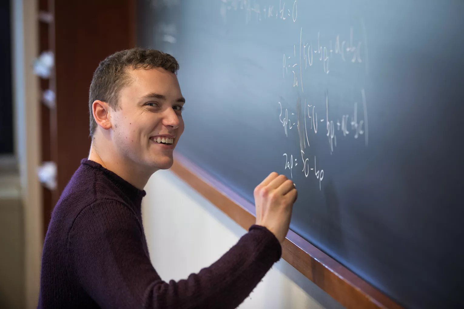 Student writes equations on chalkboard