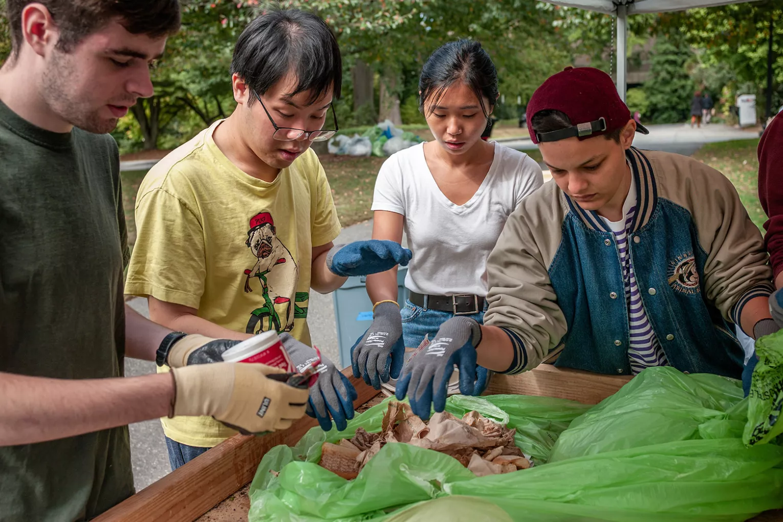 Students wearing gloves sort through waste