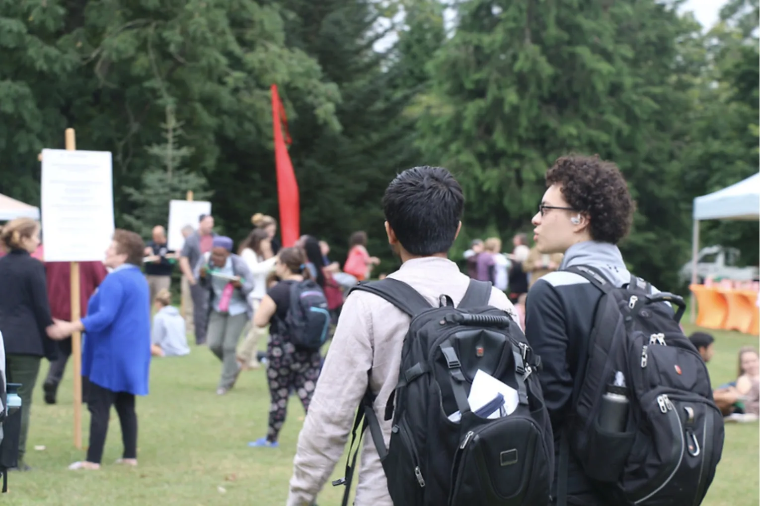 Two new students with backpacks walking on the lawn.
