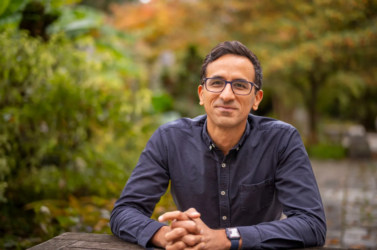 Syon Bhanot sits outdoor amid fall foliage