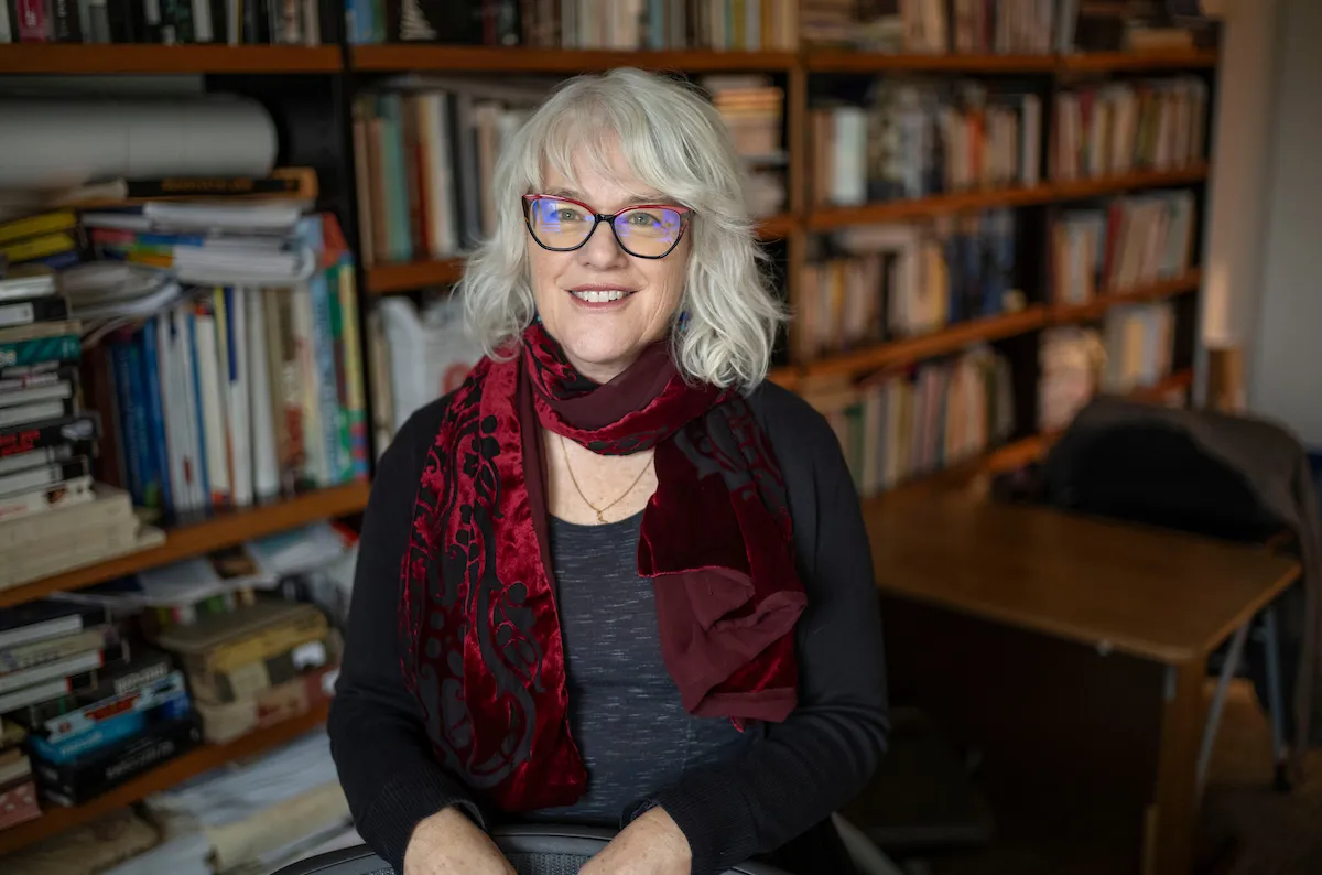 Carina Yervasi at desk in office with bookshelves behind her
