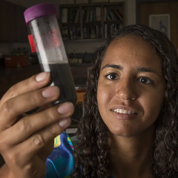 Student examines vial of red substance collected during her research.