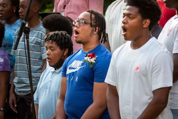 Three students sing outdoors