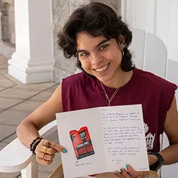 Person sitting on white Adirondack chair holds up card with writing
