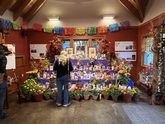 Visitors admire the ofrenda in Wister Center. It's covered in marigold and pictures of those who have passed.