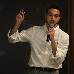 Student with microphone pitches in front of projector