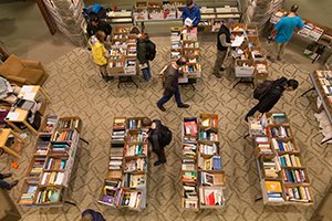 Overhead shot of people looking through table of books