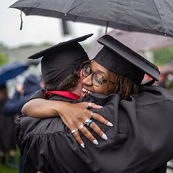 People wearing cap and gown share a hug