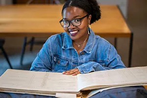 Person in blue jacket sits in library with census book open