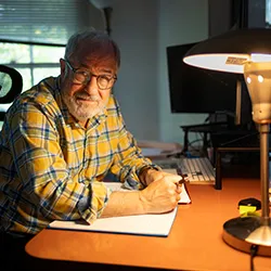 Ted Gup sitting at desk with lamp