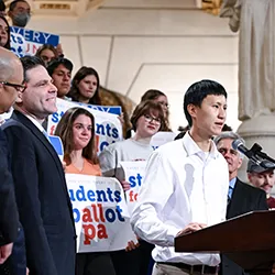 Harry Hou speaks at podium in front of group of students