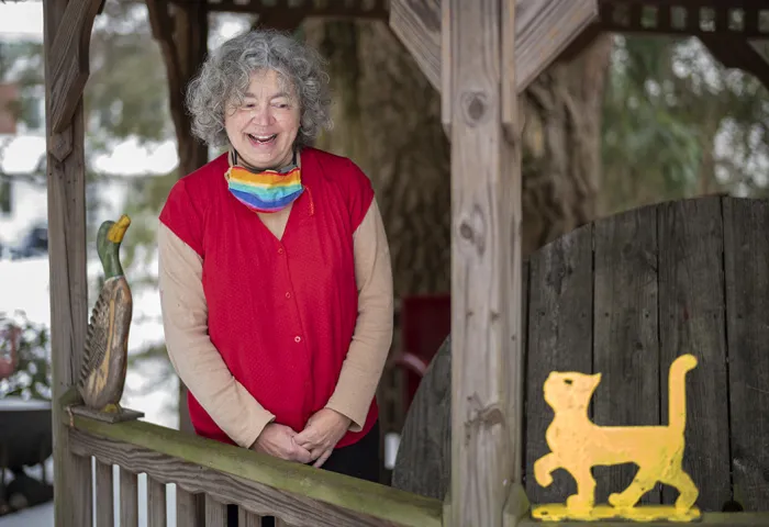 Donna Jo Napoli standing outside in winter with wooden cat perched on railing